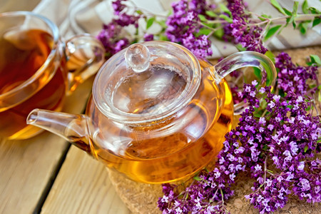 茶壶和杯子里的草药茶鲜花木板上的餐巾纸图片