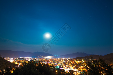 白昼和满月在夜间的城市中图片