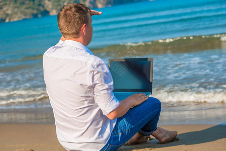 一个人在荒漠岛上用笔记本电脑寻找船图片