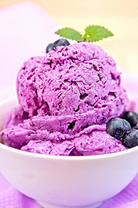 蓝莓冰淇淋夹薄荷和浆果碗里底有紫布和木板图片