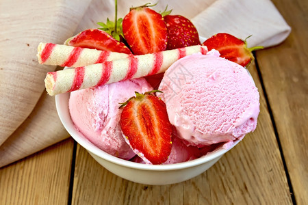 白碗中的草莓冰淇淋有和面包卷木板上的餐巾图片