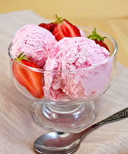 草莓和的玻璃碗中冰淇淋餐巾纸上的勺子木板背上图片