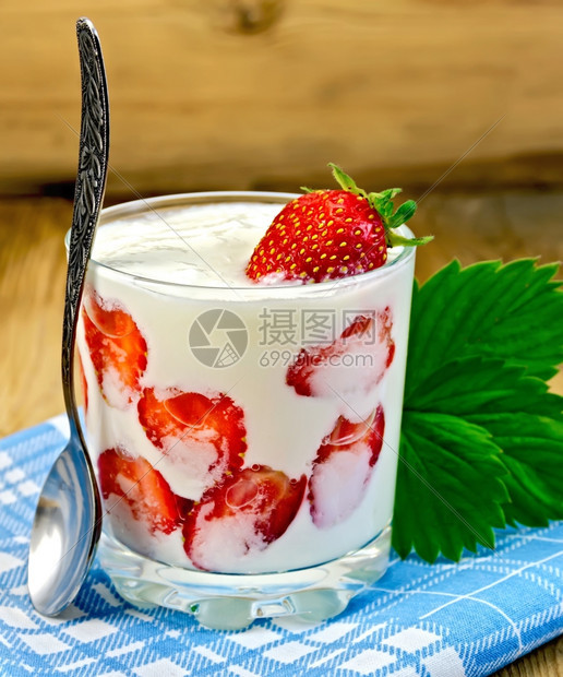 含草莓的厚酸奶和草莓的玻璃杯勺子和木板上的餐巾纸图片