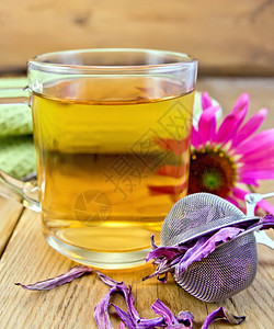 玻璃杯中的草药茶含干鲜花的叶子土木板底部的鲜花图片