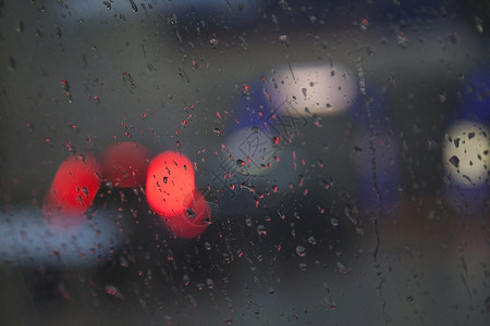 降雨时通过湿挡风玻璃看见的红色交通灯图片