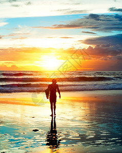 在日落的阳光下海滩上冲浪者图片