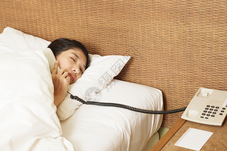 妇女在床上睡觉和打电话图片素材