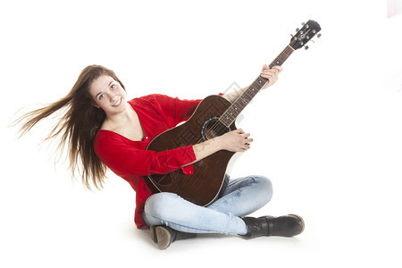 在白色背景下女孩坐在地板上抱着吉他图片