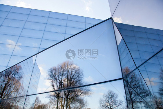 现代办公大楼的玻璃面罩有树木和蓝天空的反光图片