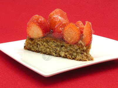 一片草莓蛋糕白盘上一片草莓蛋糕红底图片