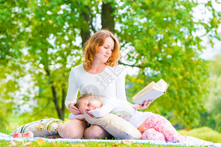 爱读书的孩子妈妈和女儿在公园看书背景