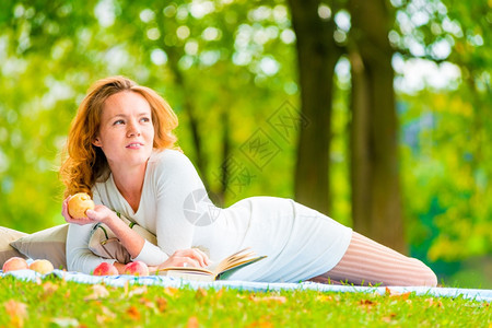 女人周末在公园休息吃着苹果图片