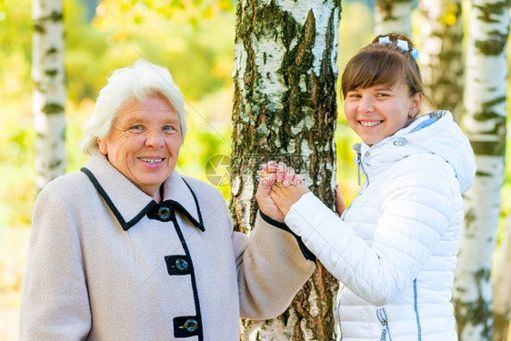 祖母和孙女在秋天公园散步图片