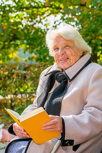 坐在长椅上的看书老年妇女图片
