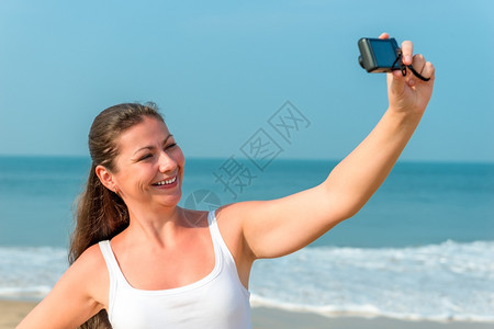 女孩在沙滩上用相机自拍图片
