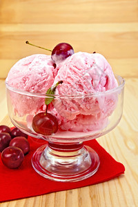 一个玻璃碗中的樱桃冰淇淋红纸巾上的浆果木板背景图片