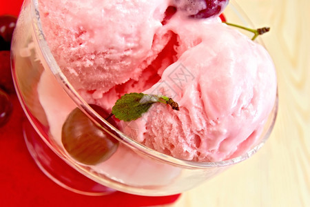 一个玻璃碗里的樱桃冰淇淋红纸巾上的浆果在木板图片