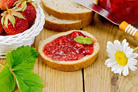 草莓果酱一罐刀子草莓在篮里甘菊在木板背景上图片
