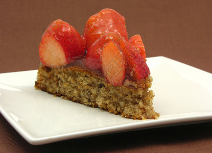 一片草莓蛋糕白盘上一片草莓蛋糕棕色背景图片