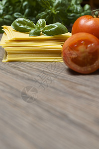 鲜意大利面条配有叶和木本背景的新鲜番茄图片