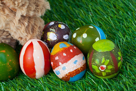 兔子坐在绿色草地上坐着青后面还有一群彩色鸡蛋可以用作复活节快乐的背景图片
