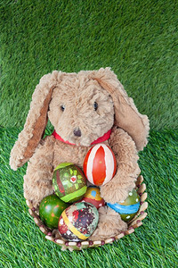兔子坐在草地上盛放彩色鸡蛋庆祝复活节快乐图片