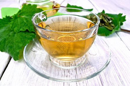 茶壶和的玻璃杯中草药茶叶本底浅木板上的红树叶图片