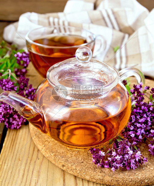 茶壶和杯子里的草药茶鲜花木板上的餐巾纸图片