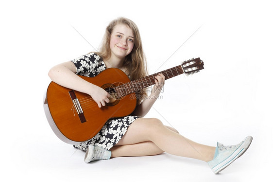 少女坐在地上弹吉他图片