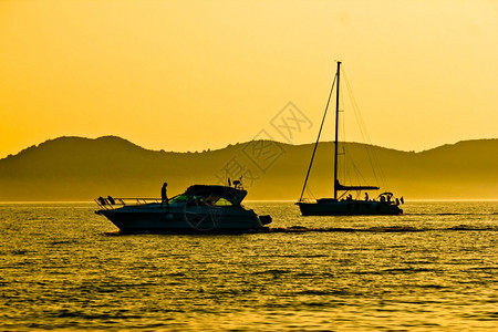 在金色日落的景下游艇和帆船双轮图片