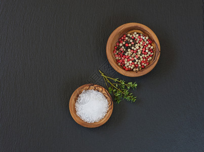 两只木碗上面有盐和多色胡椒百香料黑板上有文字空间图片