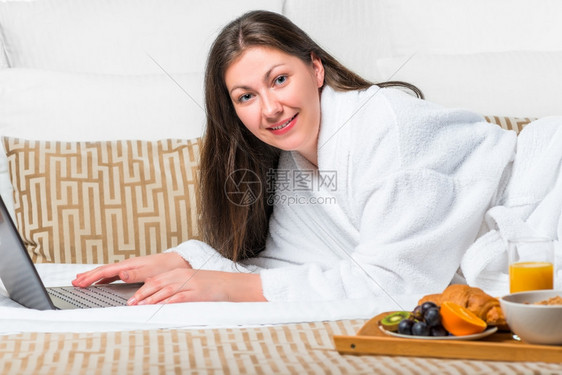 女人穿着浴袍在床上看笔记本图片