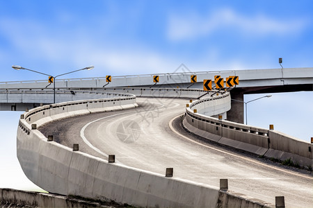 蓝色天空背景的沥青公路曲线和交通标志图片