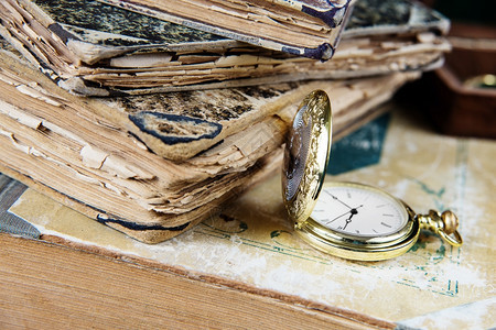 古老的黄金口袋手表有开放的封面躺在一堆旧书上图片