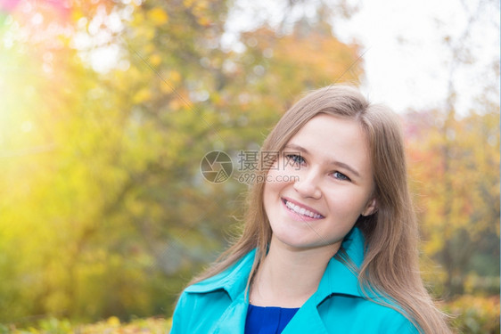 一个微笑的年轻女孩肖像在秋天自然特写图片