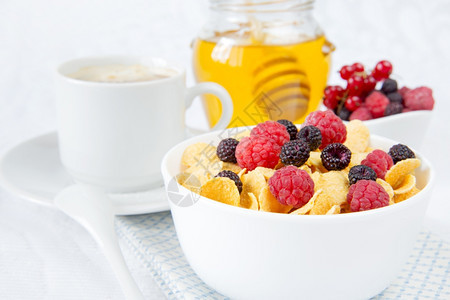 由玉米片和不同浆果蜂蜜组成的小型早餐图片