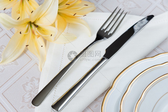 漂亮的装饰桌上面有白色板晶杯水眼镜餐巾布具和豪华桌布上的鲜花图片