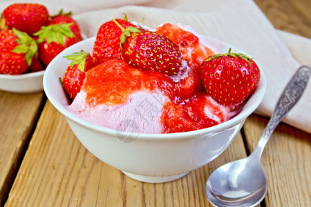 白碗中的草莓勺子木板上的餐巾纸和草莓白碗中的冰淇淋图片