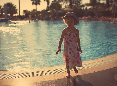 日落时在游泳池可爱小女孩的肖像图片
