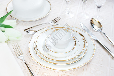 美的装饰桌上面有白色板晶杯水眼镜餐巾具和豪华桌布上的郁金花图片