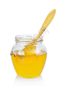 盛满一罐金蜂蜜其中浸入一勺木制的子图片