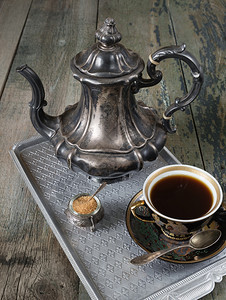 古董杯中的黑咖啡和旧木板上的古董银罐子图片