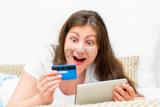 女孩惊喜地看着信用卡和平板电脑图片