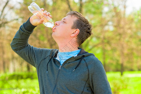一个人从小瓶子里喝水的横向肖像图片