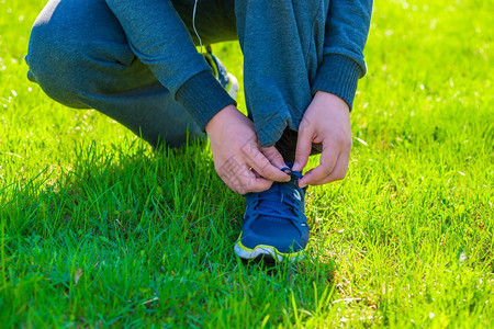 穿着运动西装的男子在草坪上系鞋带图片