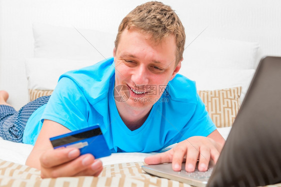 床上有信用卡的幸福男人图片
