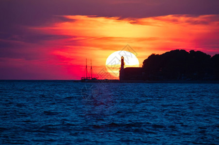 以灯塔和赛艇在zadrlmticroti的日落景图片