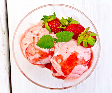 杯子里的草莓薄果和糖浆的冰淇淋放在顶上背景浅木板图片