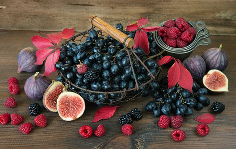 篮子中的黑葡萄和成熟无花果红草莓和木本底有秋叶的黑莓图片