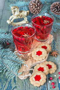 圣诞餐桌两杯红热辣味葡萄酒配香料牛莓和饼干配果酱围着圆形树枝和锥图片